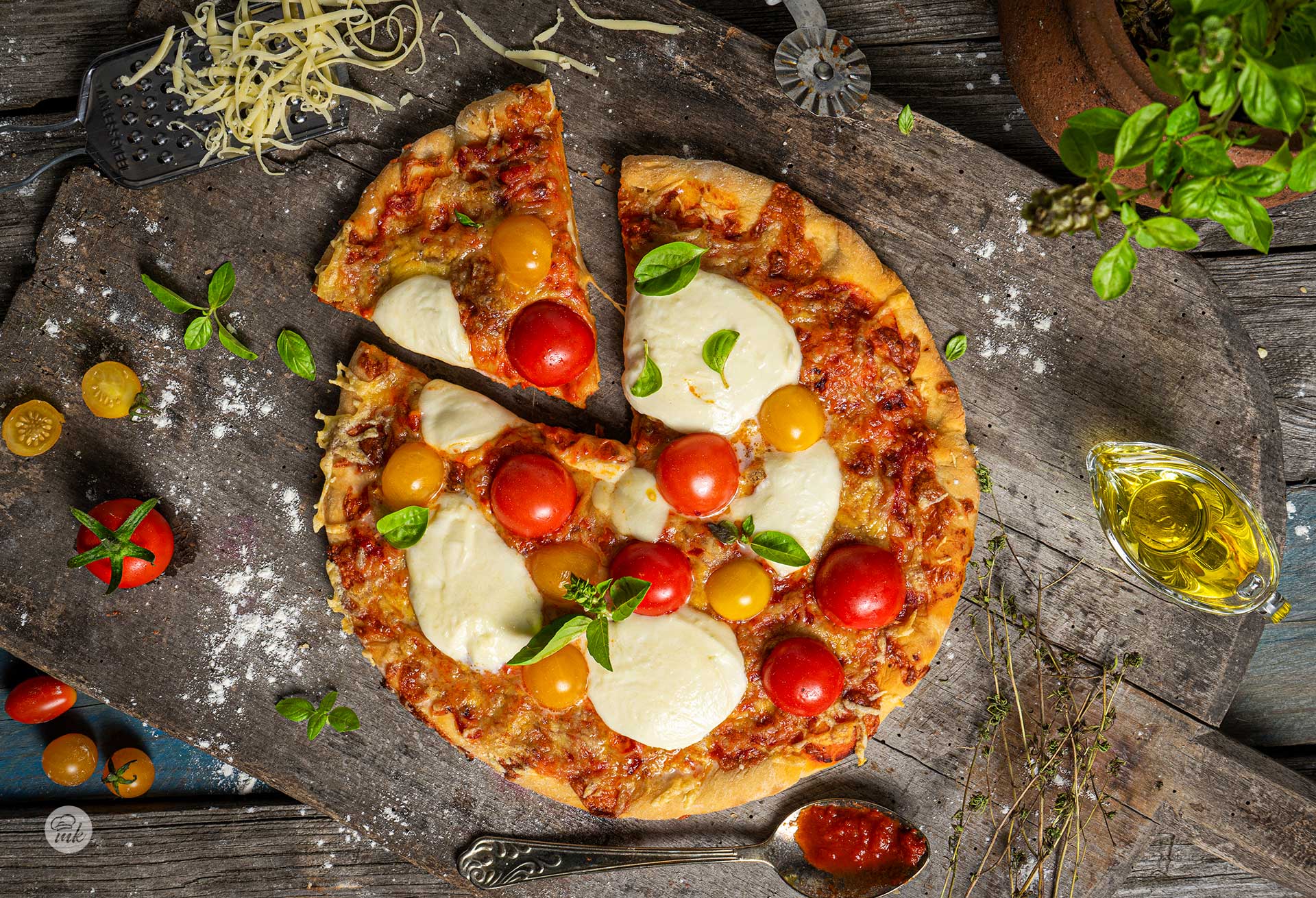 Пица с шунка и кашкавал заснета отгоре, поръсена с моцарела, чери домати и пресен босилек, положена на стара дървена маса