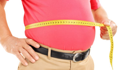 Мъж с наднормено тегло измерва с шивашки метър талията си