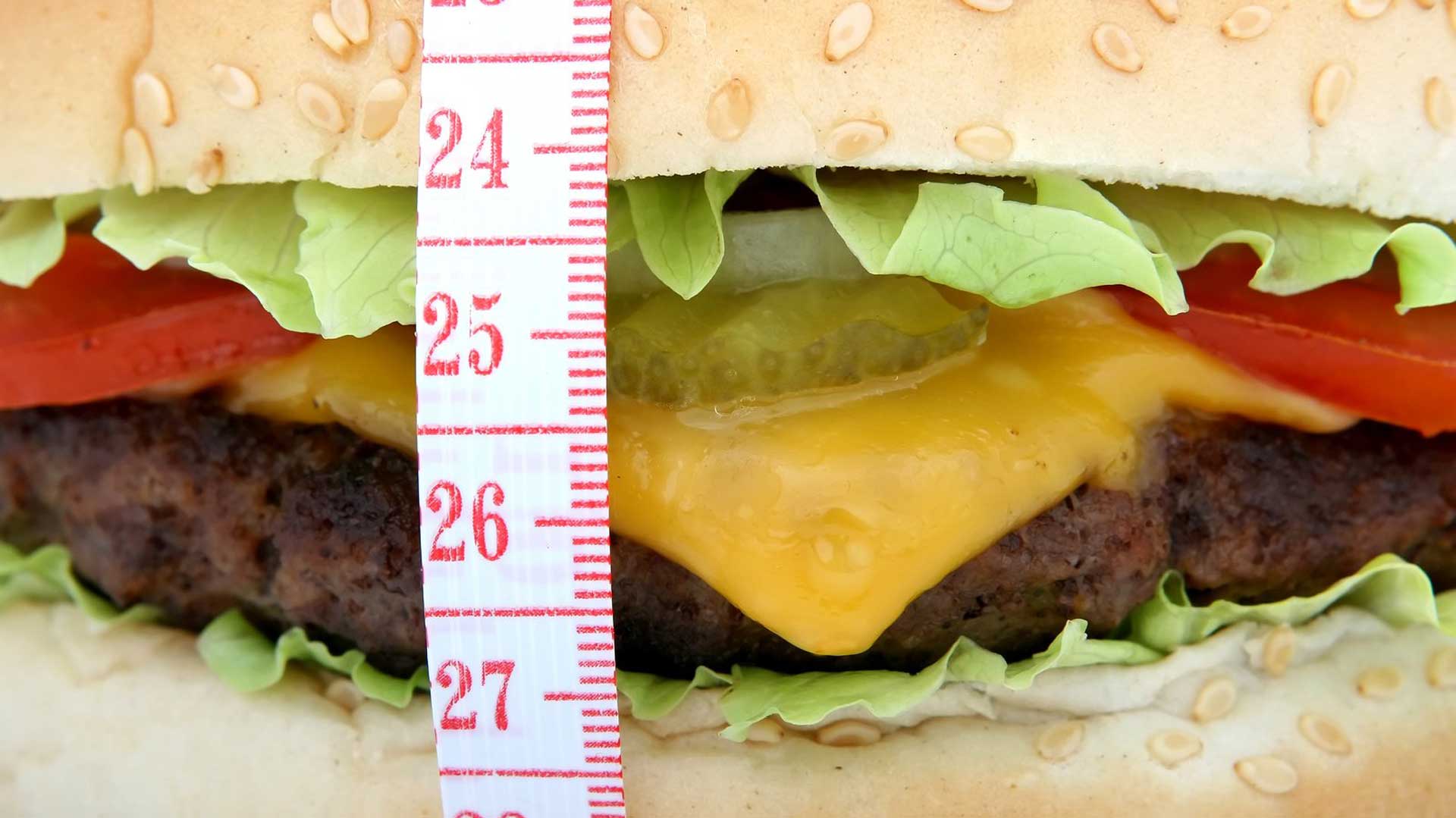 Хамбургер, опасан със сантиметър, свързан със статия за децата с наднормено тегло