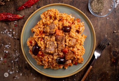 Порция свинско с ориз, праз и маслини, снимана отгоре
