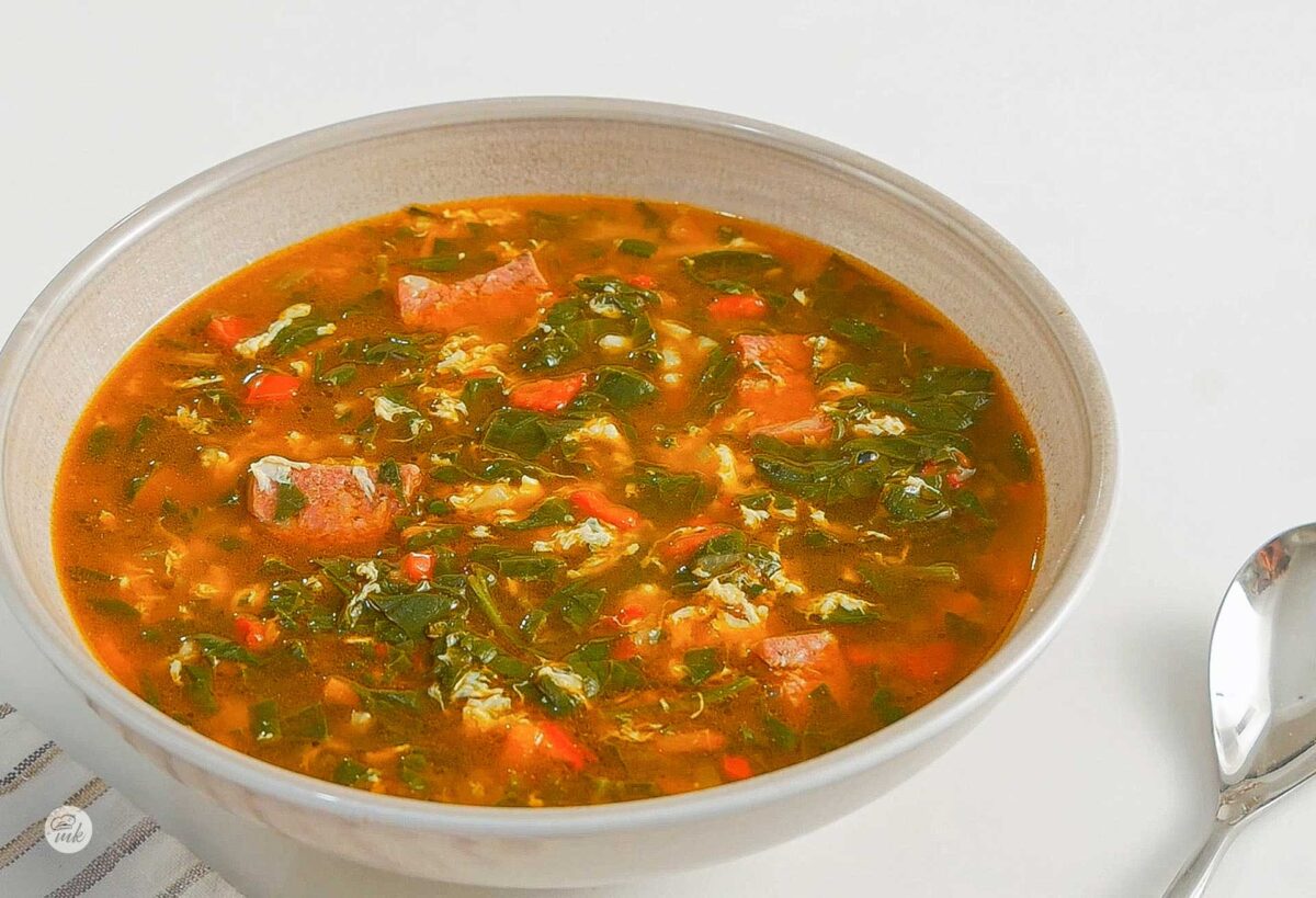 Супа със спанак и бабек в бяла купичка, снимана отпред