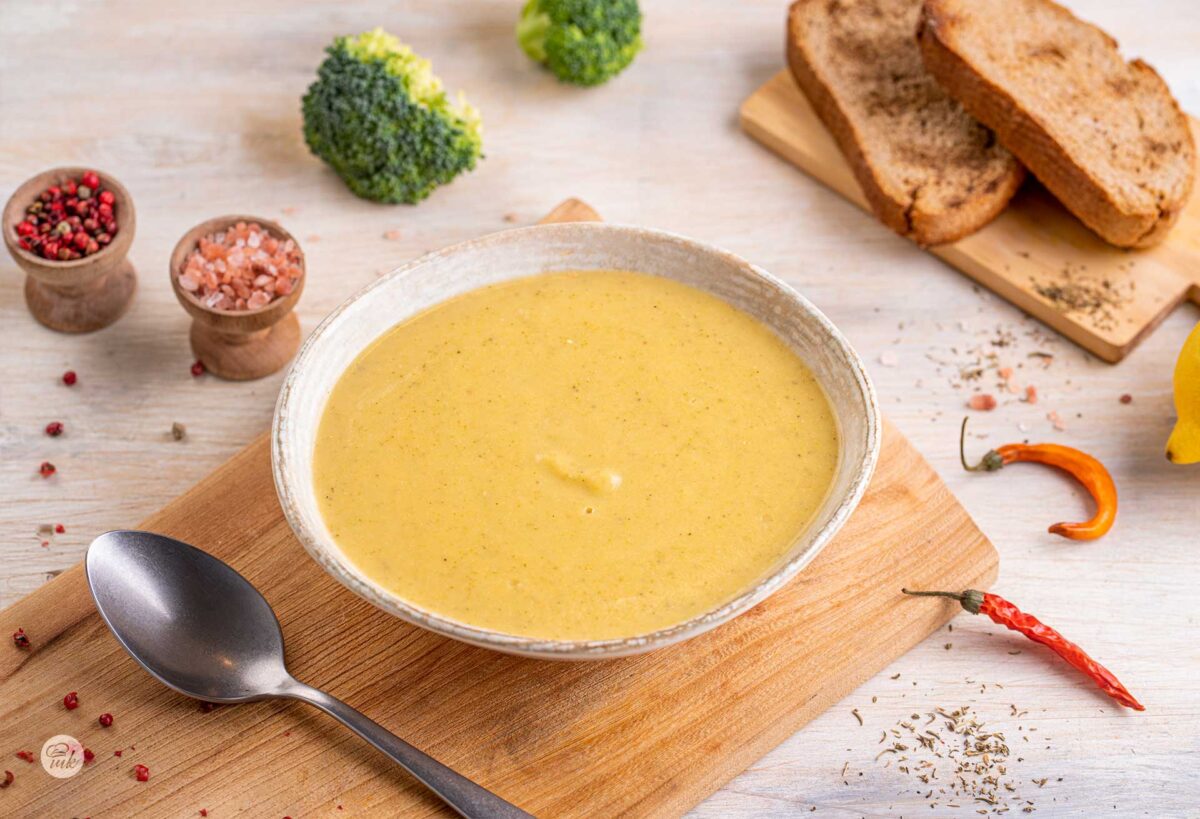 Крем супа от карфиол, броколи и картофи в бяла порцеланова купа, върху дървена дъска, поглед от горе.